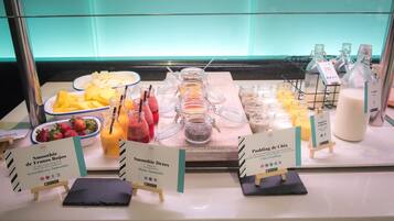 Un bufé con diversas opciones de comida y bebida, incluyendo batidos y jugos.