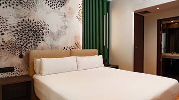 Habitació d'hotel moderna amb un llit gran, un panell de separació verd i una obra d'art abstracta decorativa a la paret.