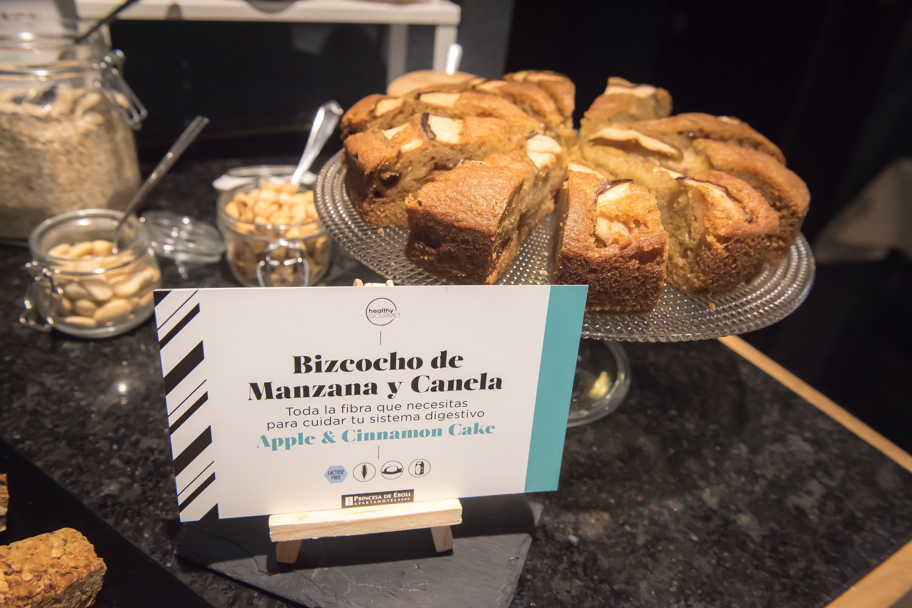 A display of a cake named Bizcocho de Manzana y Canela, featuring apple and cinnamon flavors.