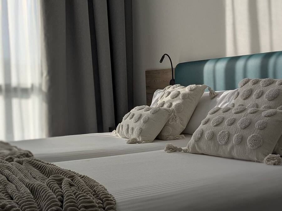 Un dormitorio moderno con una cama, almohadas y una manta.