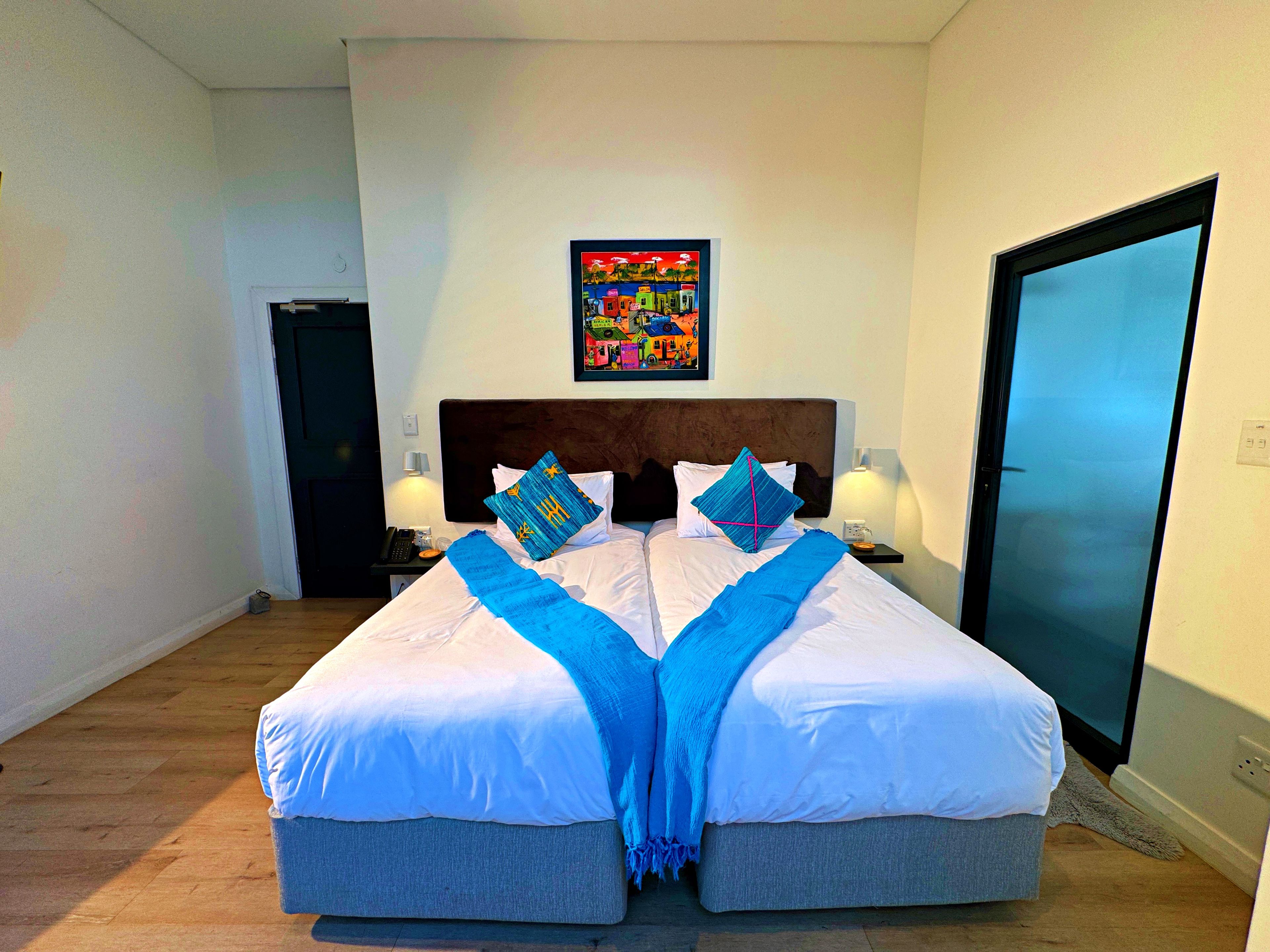 A hotel room with a large bed, two bedside lamps, a nightstand, and a door.