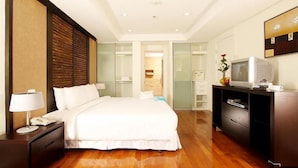 Une chambre d’hôtel avec un grand lit, une table de chevet avec une lampe, un téléviseur posé sur un meuble et une commode.