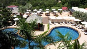 Un complexe hôtelier doté d’une piscine, de chaises longues, de parasols et offrant une vue sur la mer et un navire de croisière.