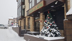 A hotel with a snow-covered entrance and a decorated Christmas tree.