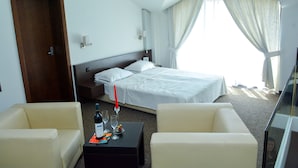 A hotel room with a bed, two chairs, a small table with a bottle and glasses, and a door. - Hotel Elitsa (Bansko)