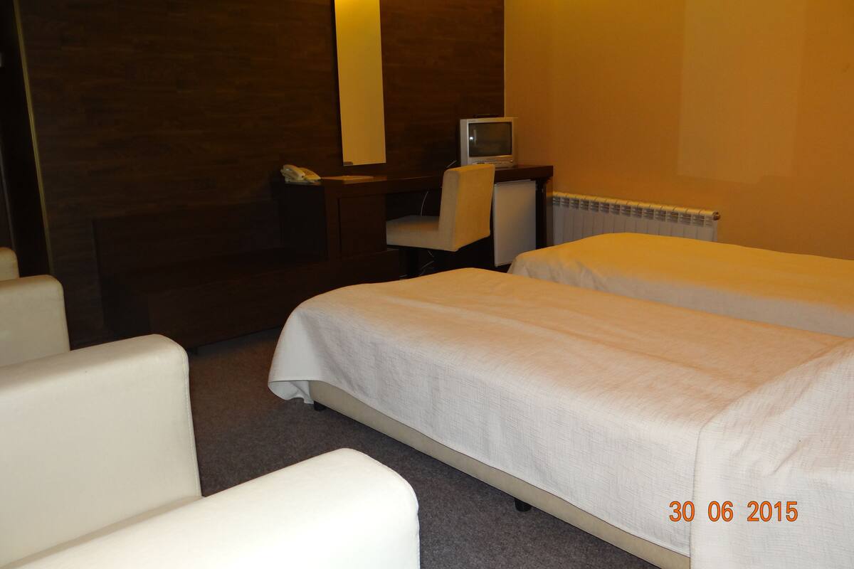 A hotel room with two beds, a desk with a TV, a chair, and a large mirror.