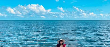 En person sitter på en SUP-bräda (ståbräda) på stilla vatten ute i havet, under en klar himmel.
