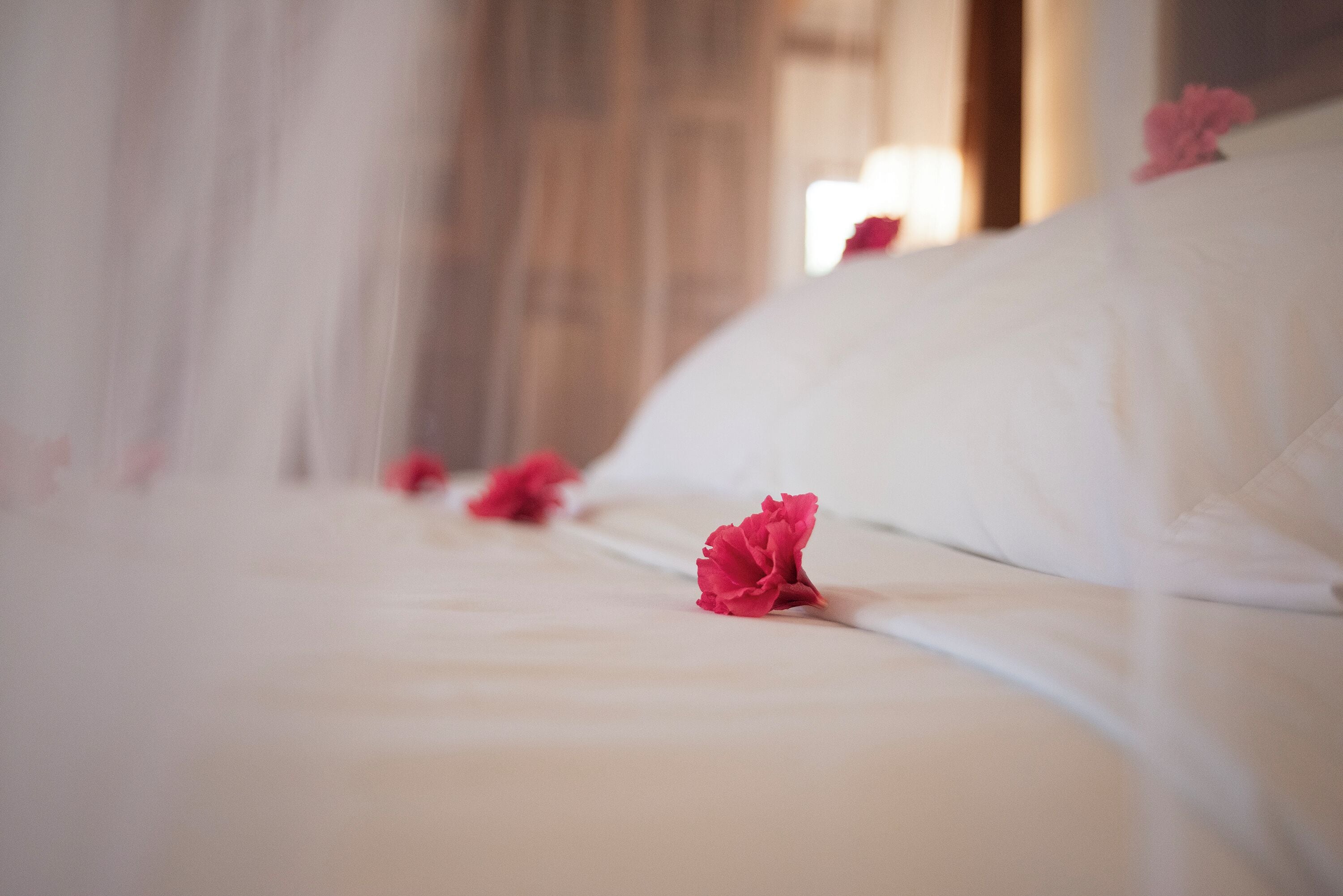 A bed with white linens and pink flowers.