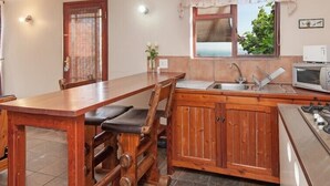 Una cocina con mesa de madera, pileta, estufa y microondas.