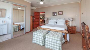A bedroom with a wooden bed, two bedside tables, a mirror, a wardrobe, and a bathroom with a sink and mirror.