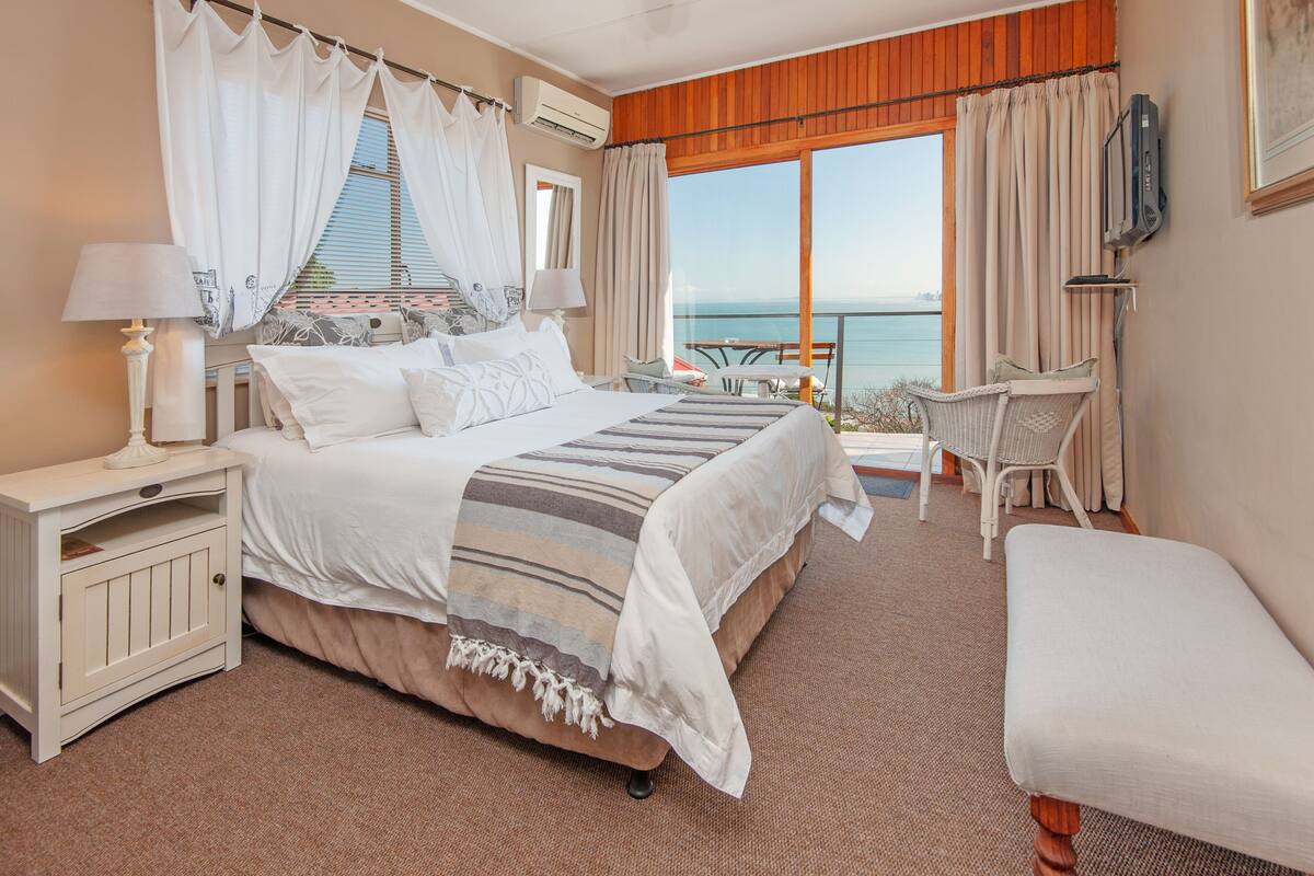 Ein Schlafzimmer mit einem großen Bett, einem Nachttisch, einem Sessel und Meerblick.