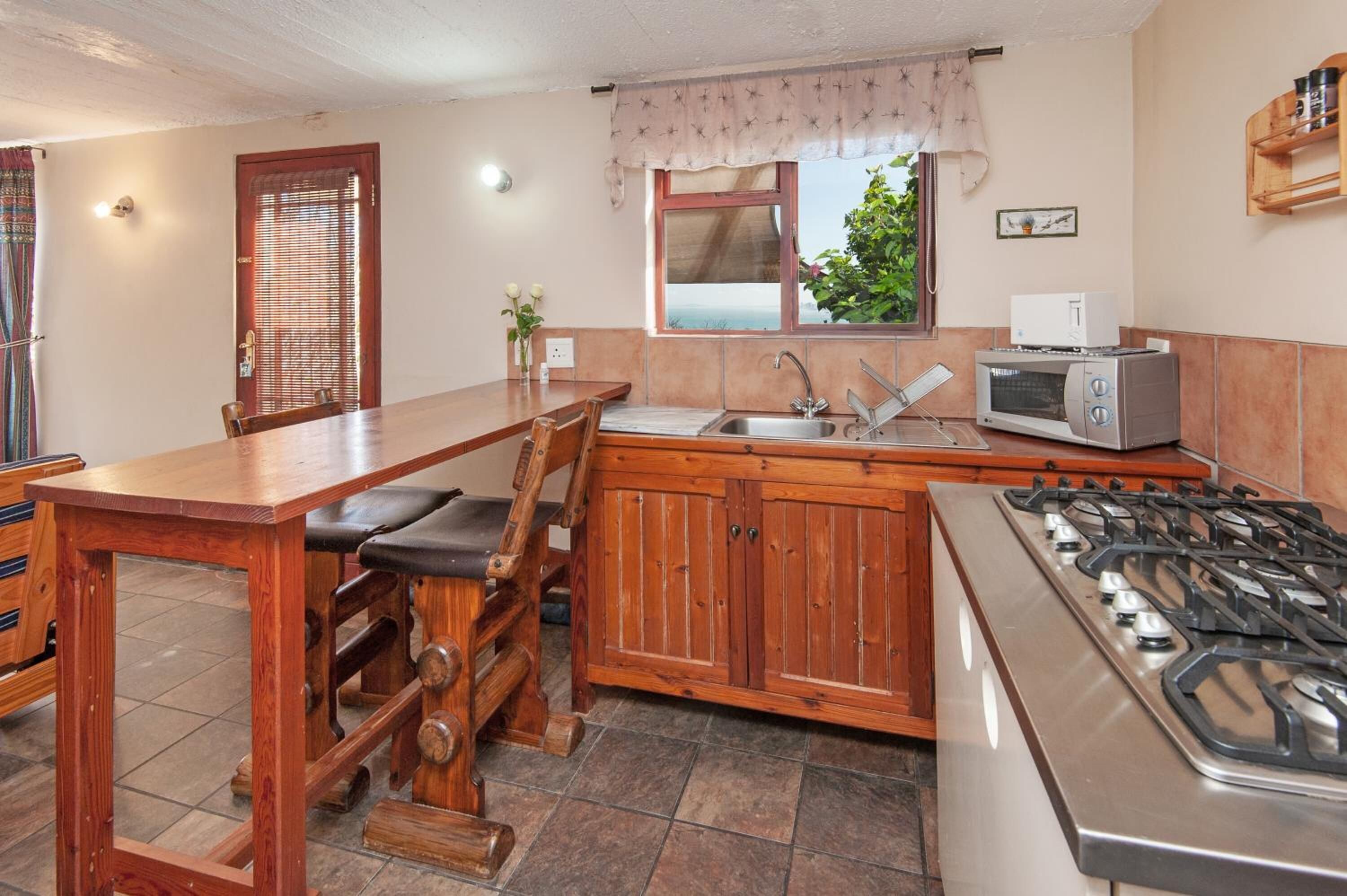 Une cuisine compacte avec une table en bois, un évier encastré, un four à micro-ondes et une cuisinière à gaz.