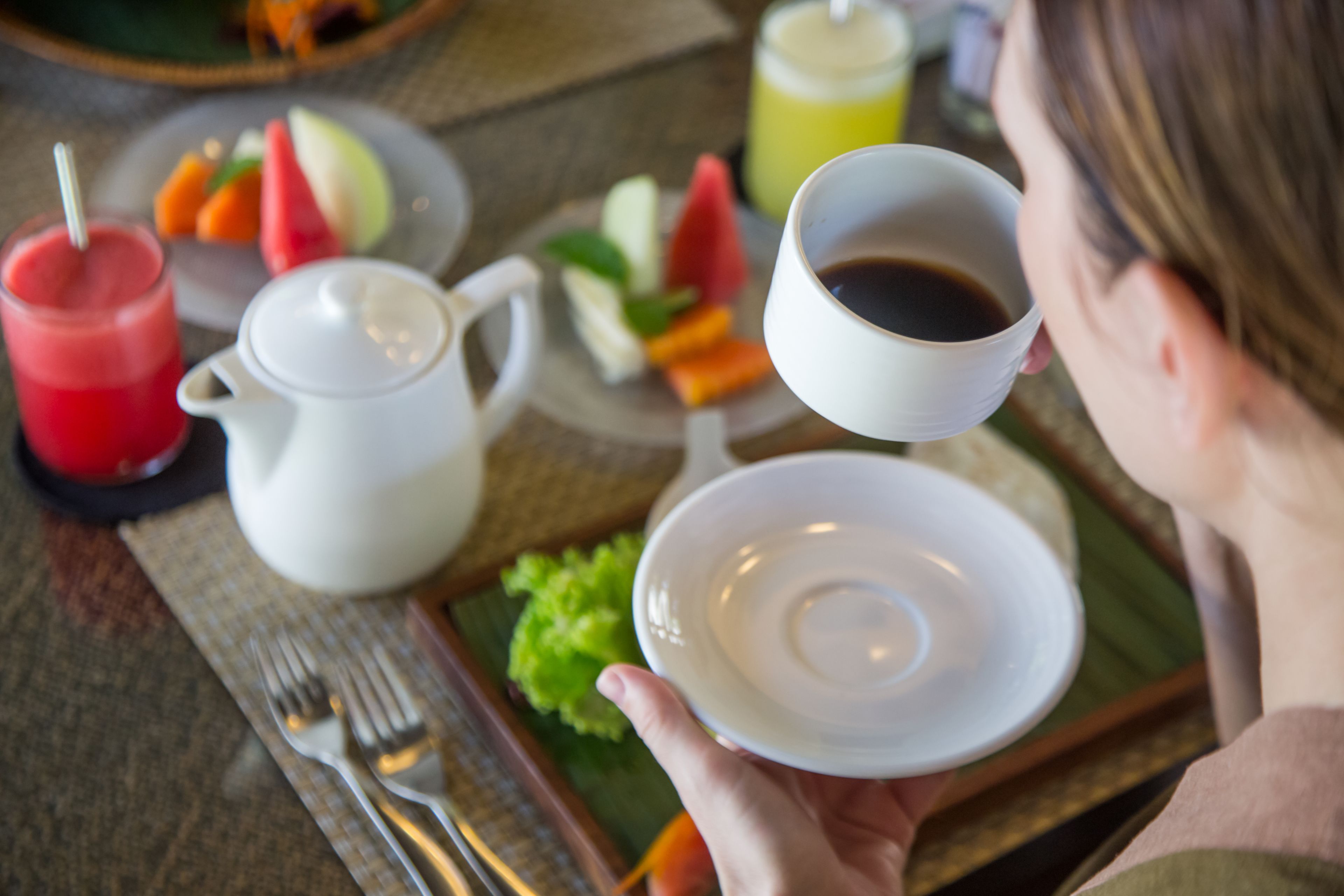 A breakfast setting with a plate of food, a cup of coffee, and a glass of juice.