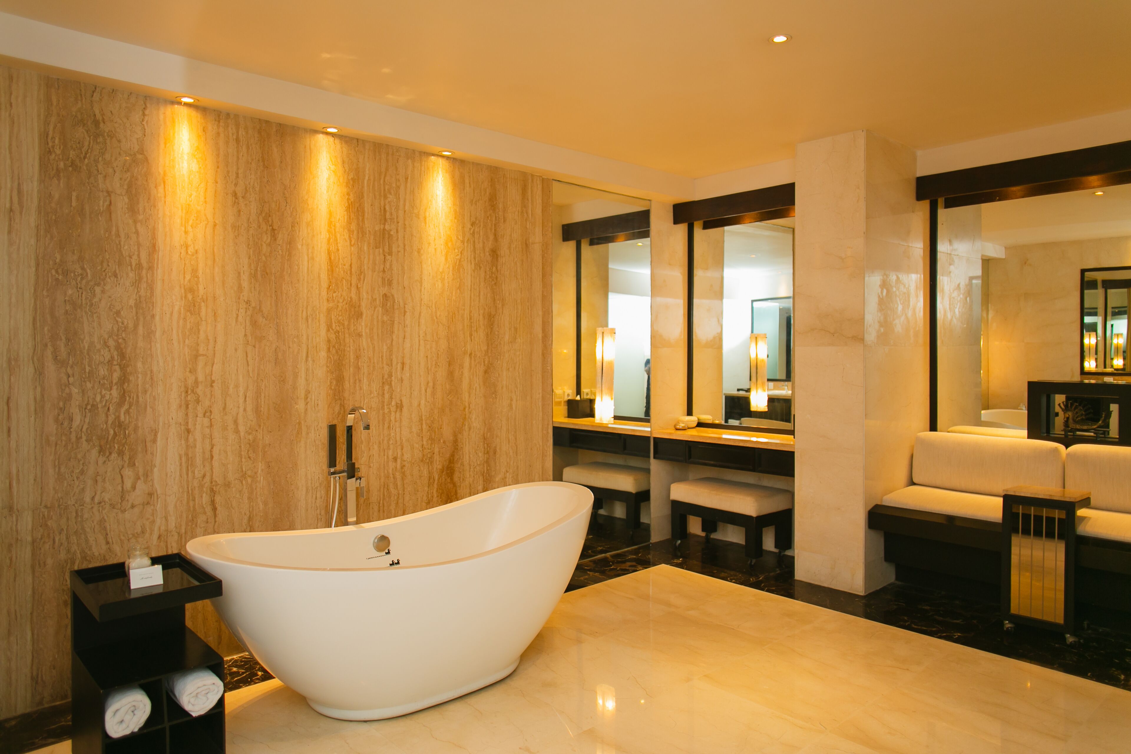Ein modernes Badezimmer mit einer freistehenden Badewanne, einem Waschtisch mit Spiegel und einer Sitzecke mit einer Couch.