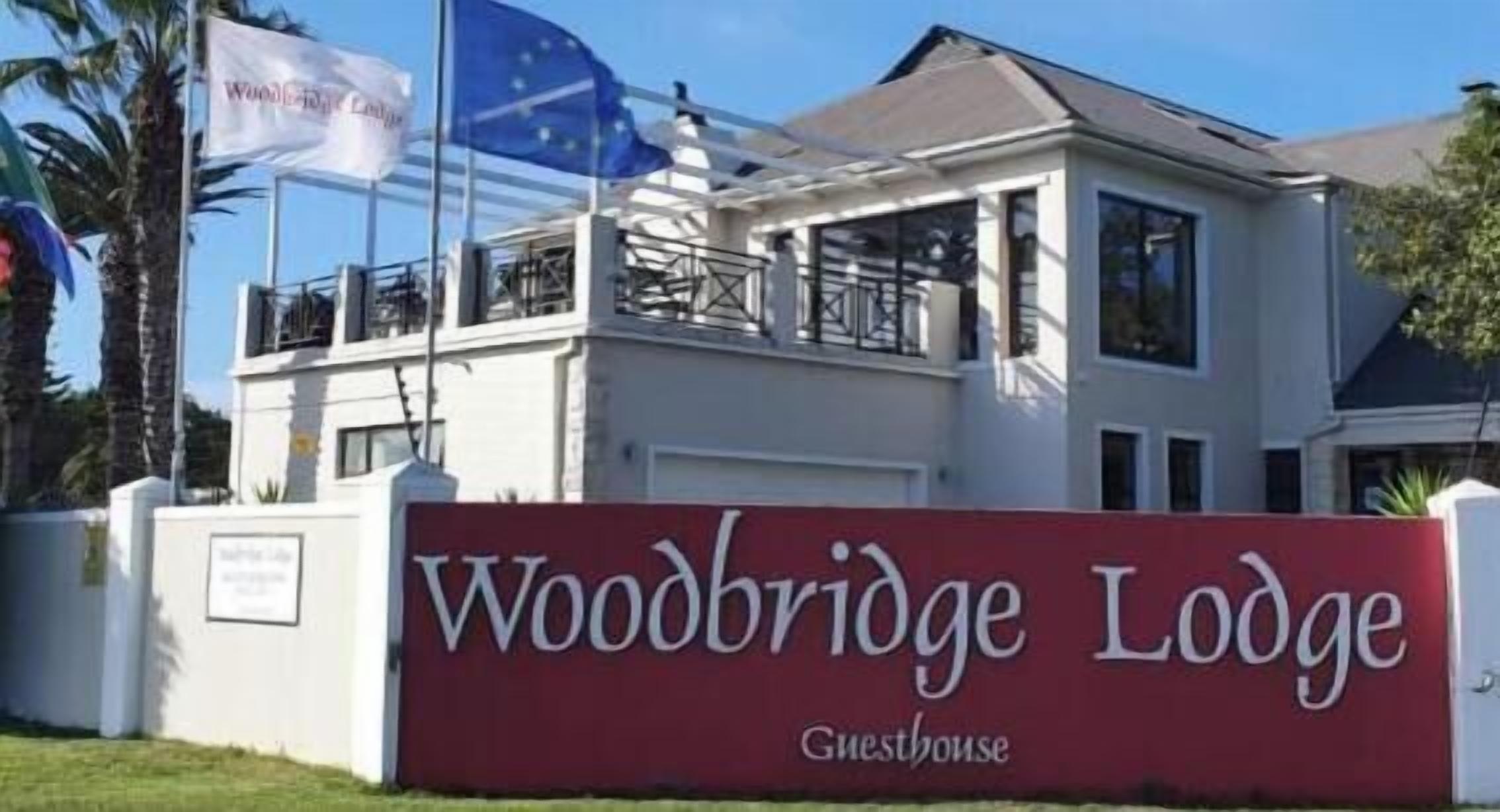 Ein zweistöckiges Gebäude mit einem Schild, auf dem 'Woodbridge Lodge Guesthouse' steht.