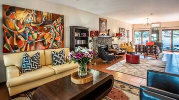 Relax in this inviting living room with a fireplace, bookshelf, and large window offering a view of the outdoors.