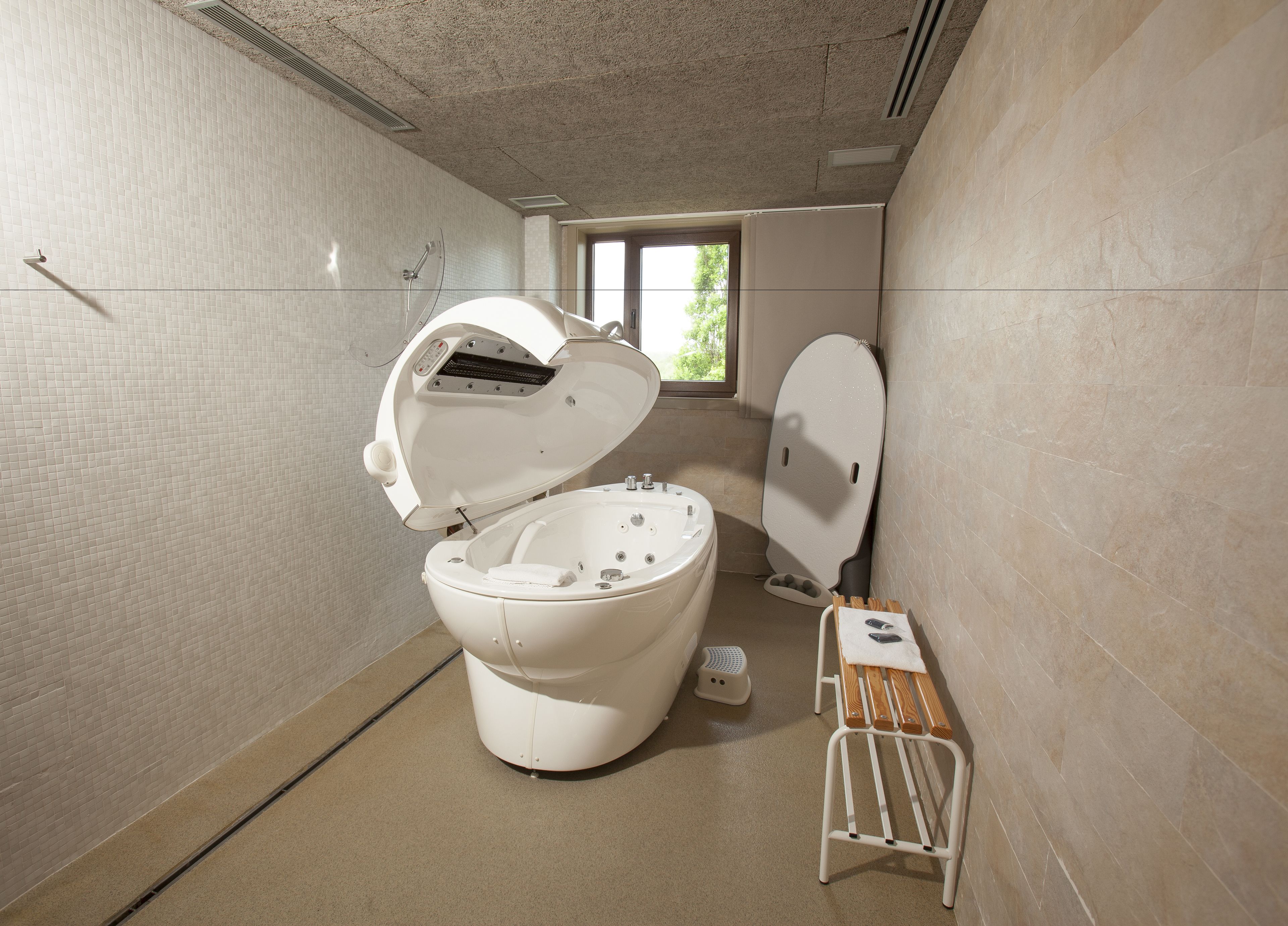 Un baño moderno con inodoro blanco, un bidé y un pequeño banco de madera.