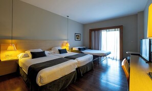 A hotel room with two beds, a desk, a chair, a TV, and a window with curtains.
