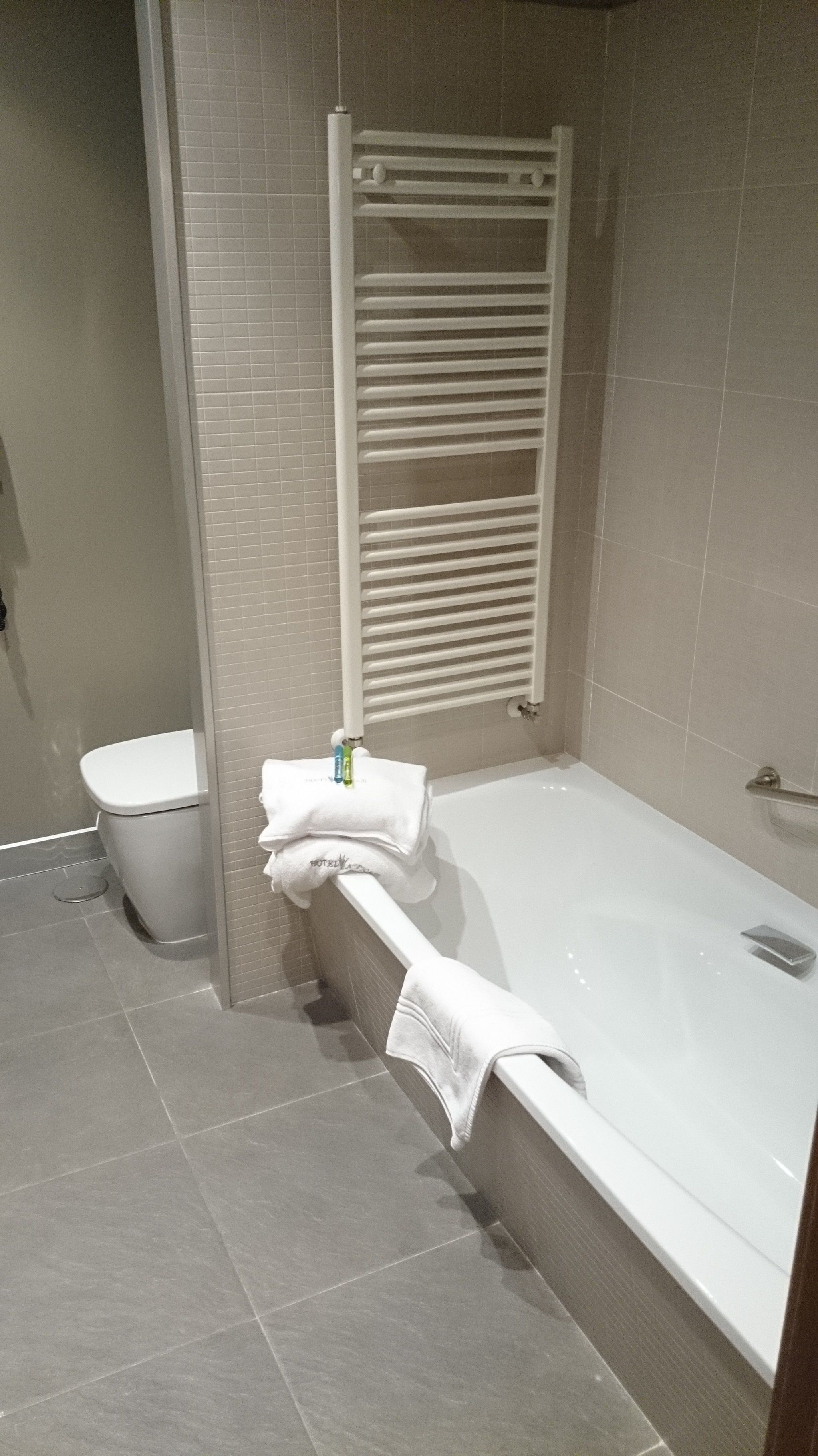 A bathroom with a bathtub, toilet, and towel rack.