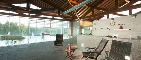A spacious indoor area with a pool, seating, and a reception desk.