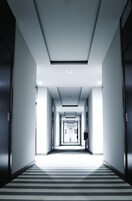 A hotel corridor with a striped carpet, recessed lighting, and doors on both sides.