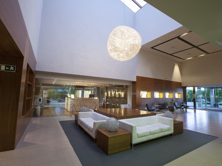 Eine geräumige Lobby mit hoher Decke, einem großen Holzerreptionsschalter und Sitzbereichen.