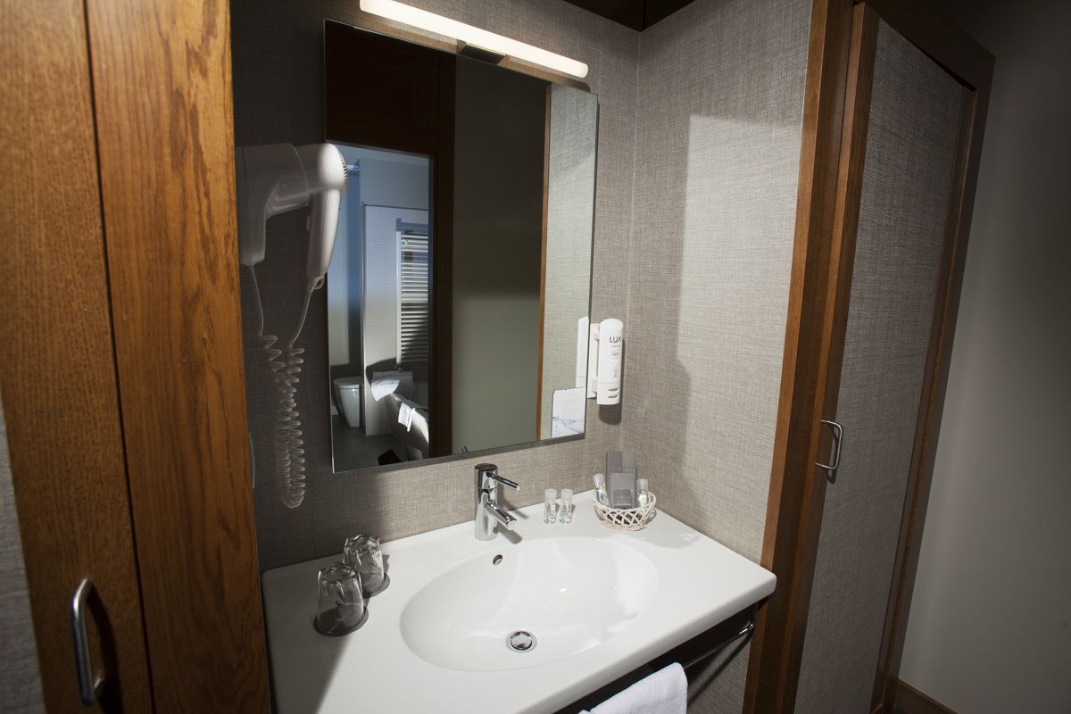 Een hotelbadkamer met een witte wastafel, een spiegel en een handdoekhouder.