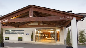 L’entrée d’un hôtel, avec un auvent en bois, une enseigne indiquant « HOTELSPA ATTICA21 » et une porte vitrée donnant sur l’intérieur.