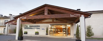 A hotel entrance with a wooden overhang, a sign reading "HOTELSPA ATTICA21," and a glass door leading inside.