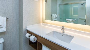 A modern bathroom with a white sink, mirror, and wooden vanity.