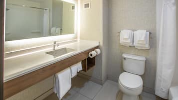 A modern bathroom with a large mirror, a sink, a toilet, and a shower curtain.