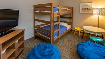 A bunk bed with a TV, a small table, and two bean bags in a room with a carpeted floor.