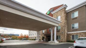 Een Holiday Inn Express & Suites met een overdekte parkeerplaats en een gevel van natuursteen.