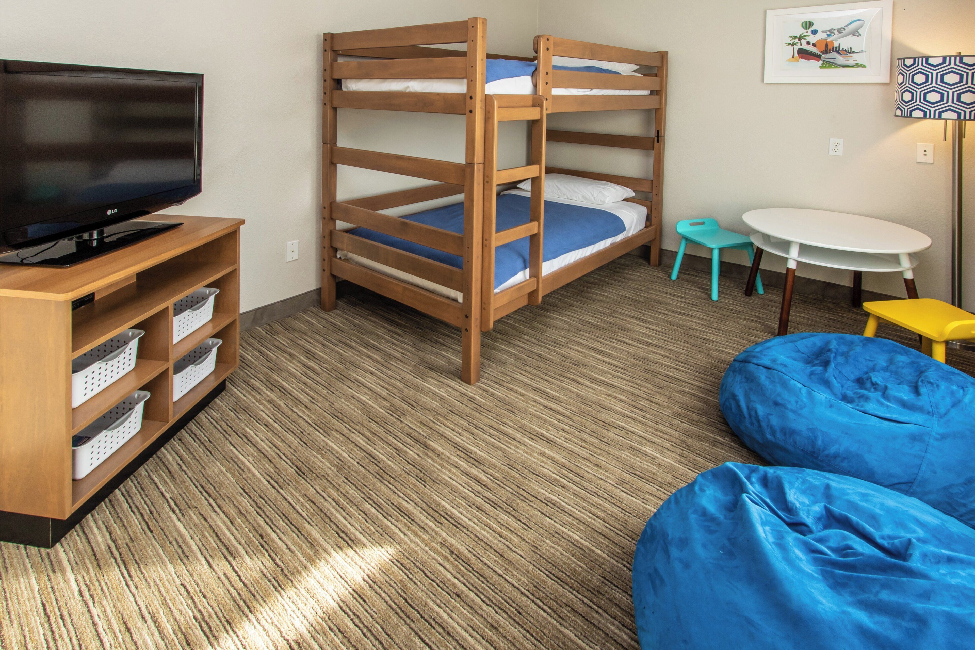 A room with bunk beds, a television, a small table, and a bean bag.