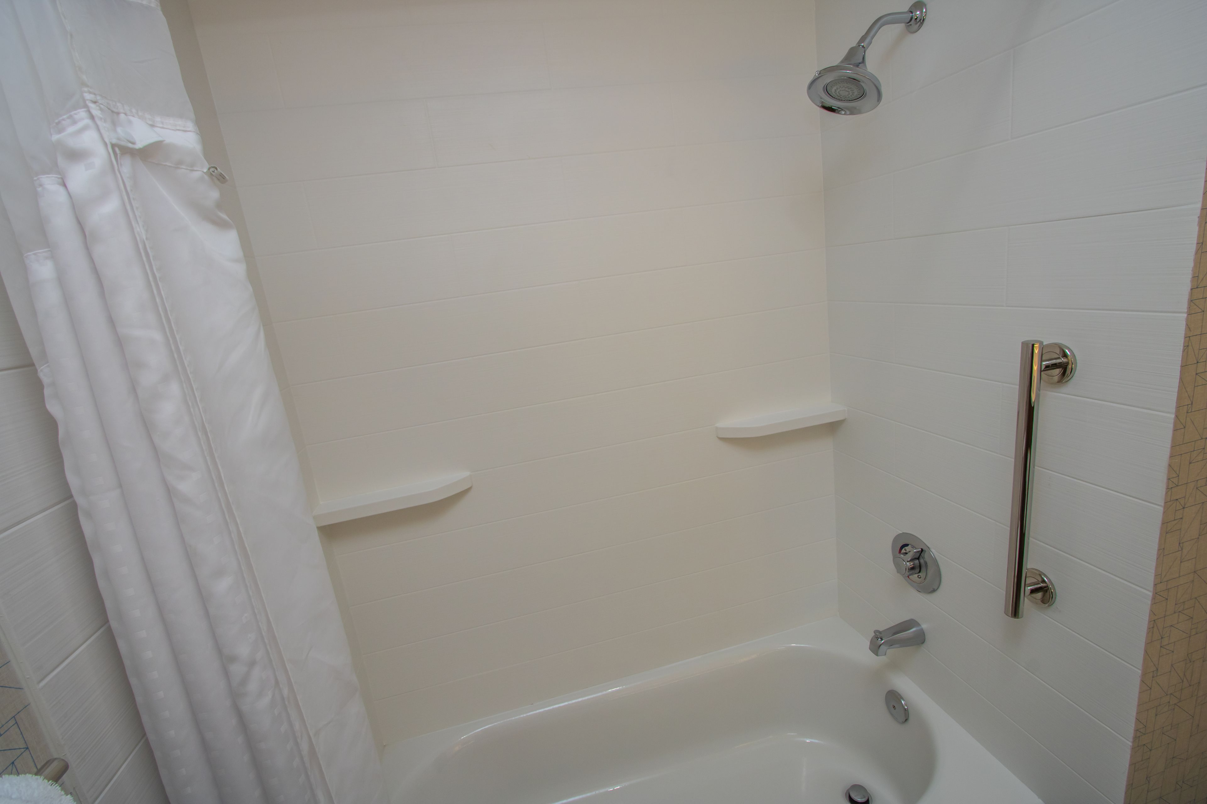 Une salle de bain moderne équipée d’une baignoire, d’une douche et d’une barre d’appui.