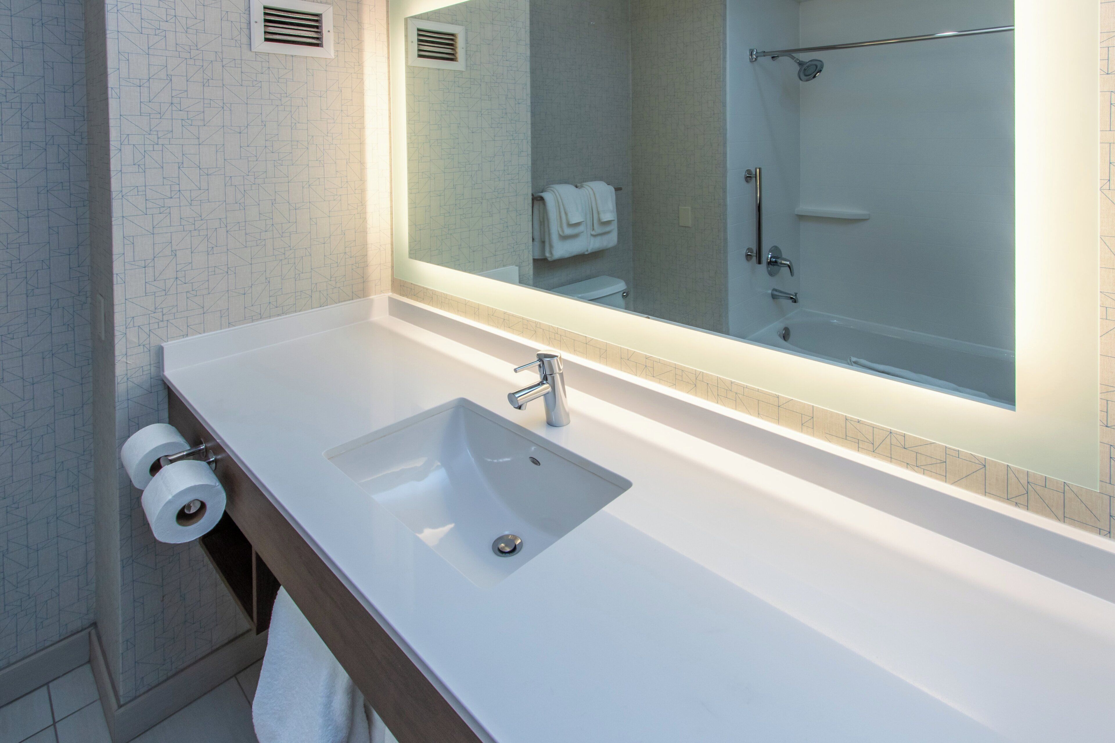 Een badkamer met een wit wastafel, een spiegel en een douche.