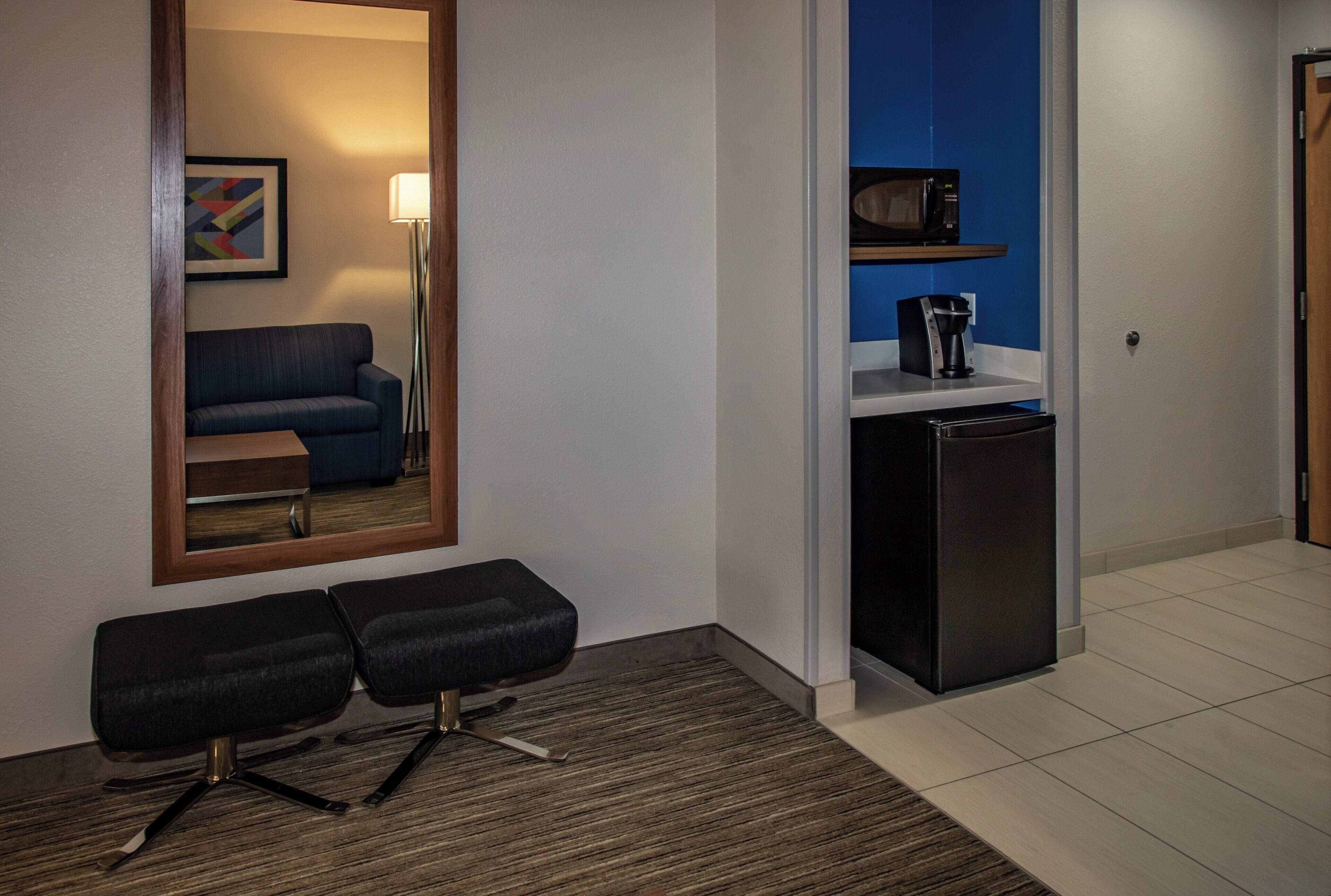 Une chambre d’hôtel équipée d’un canapé, d’une petite table, d’une machine à café et d’un réfrigérateur.
