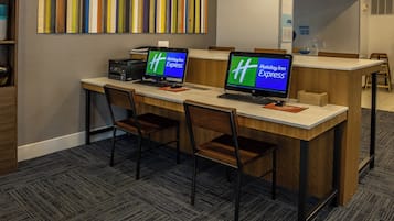 Een receptiebalie met twee computerschermen waarop het Holiday Inn Express logo staat, een printer en een aantal stoelen.