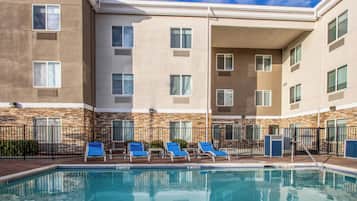 A hotel with a swimming pool, multiple balconies, and a stone facade.
