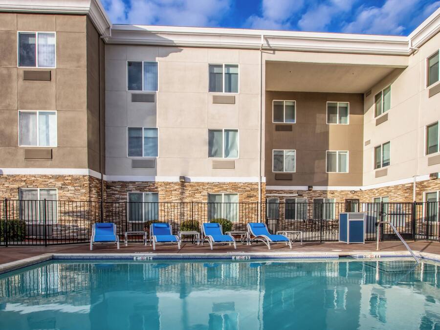 A hotel with a swimming pool, multiple balconies, and a stone facade.