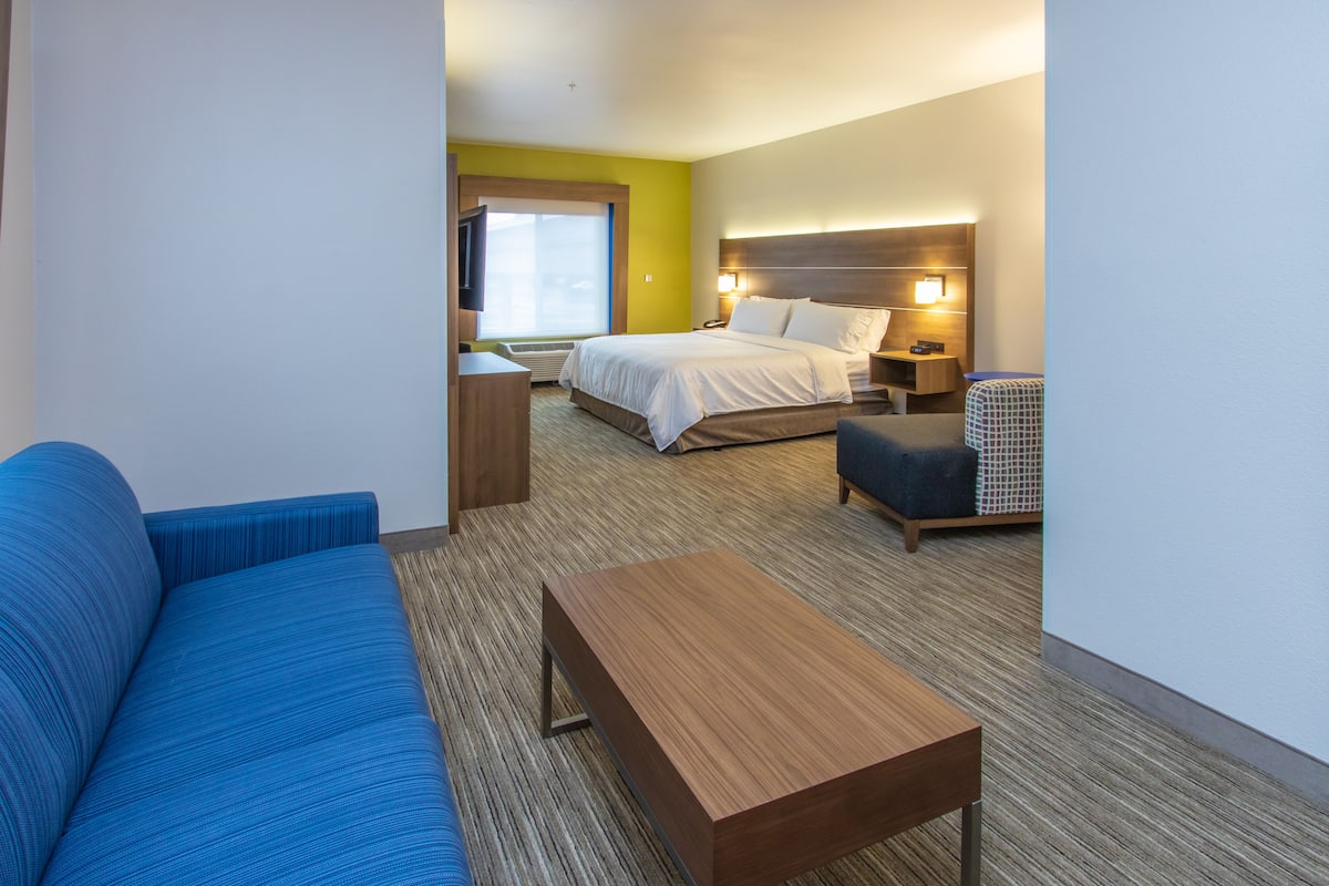 A hotel room with a bed, a sofa, a small table, and a nightstand.