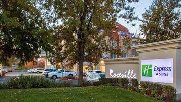 A hotel sign with 'Roseville Express & Suites' and a parking lot with several cars.