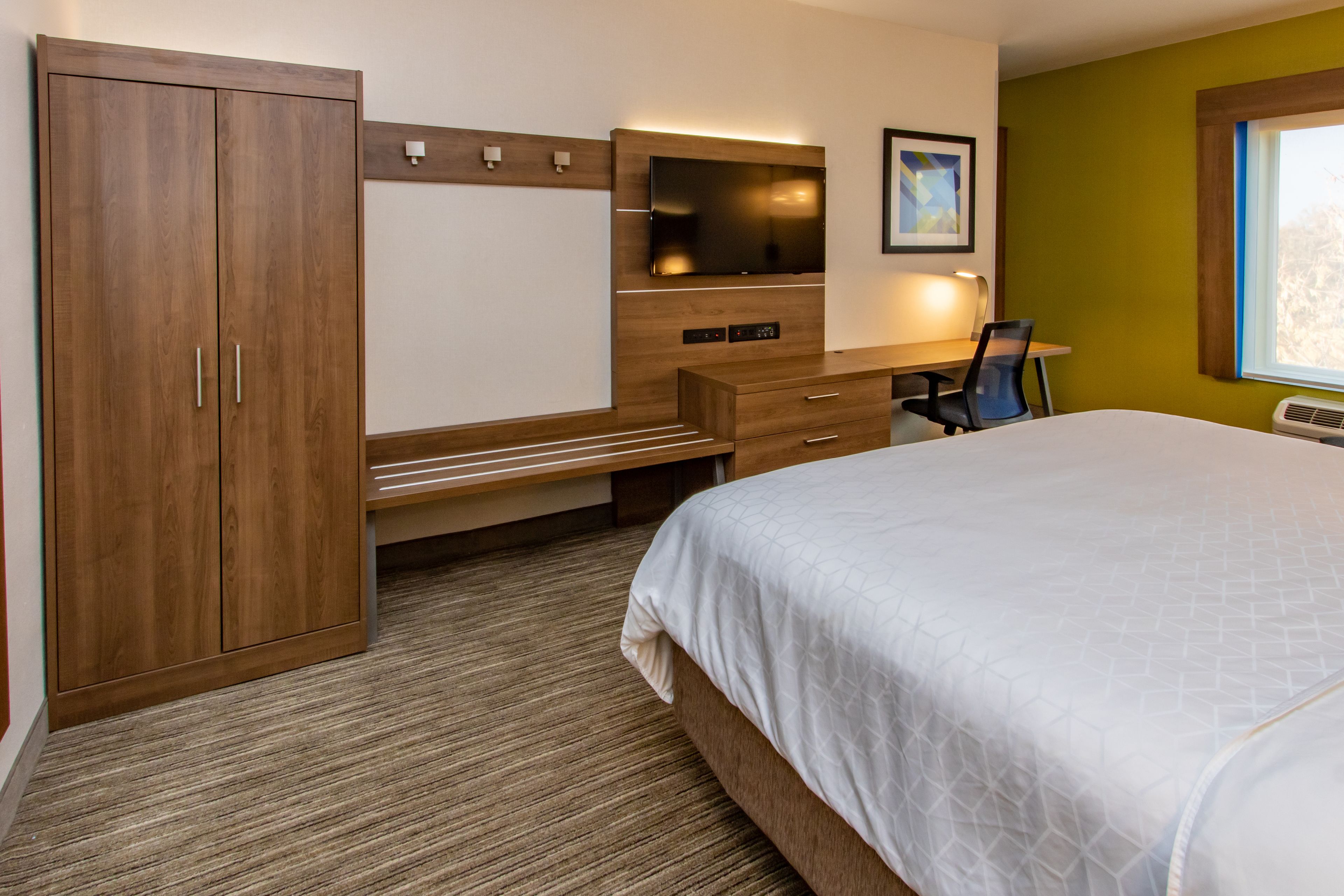 Ein Schlafzimmer mit Bett, Schreibtisch, Stuhl und Kleiderschrank.