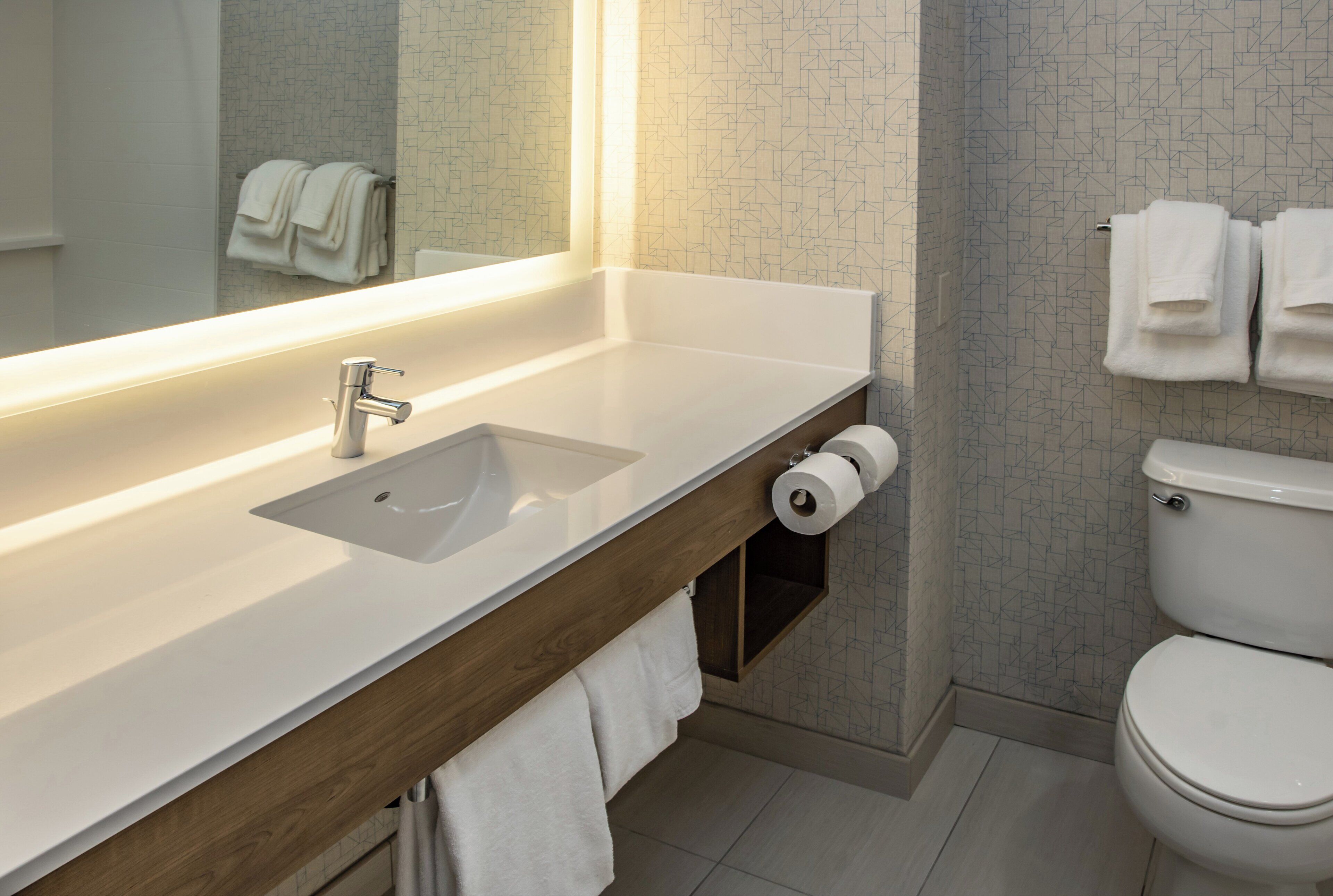A modern bathroom with a white sink, mirror, and toilet.