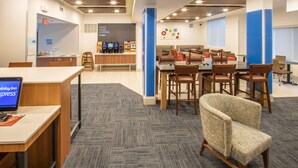 Un vestíbulo de hotel con una barra de café, zona de estar y el letrero de Holiday Inn Express.