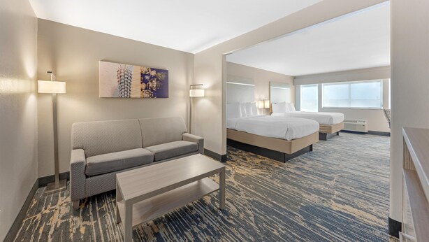 Una habitación de hotel con sofá, cama, escritorio y un ventanal grande.