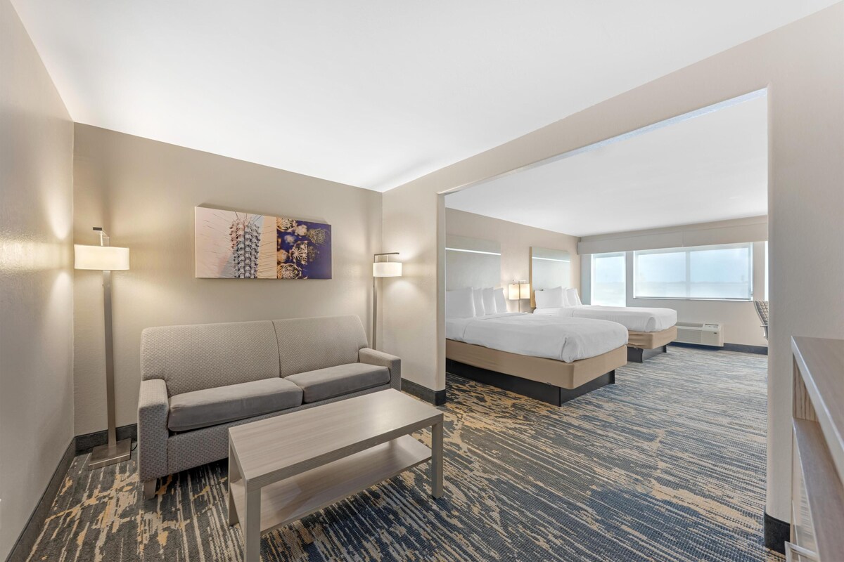 A hotel room with a sofa, a bed, a desk, and a large window.