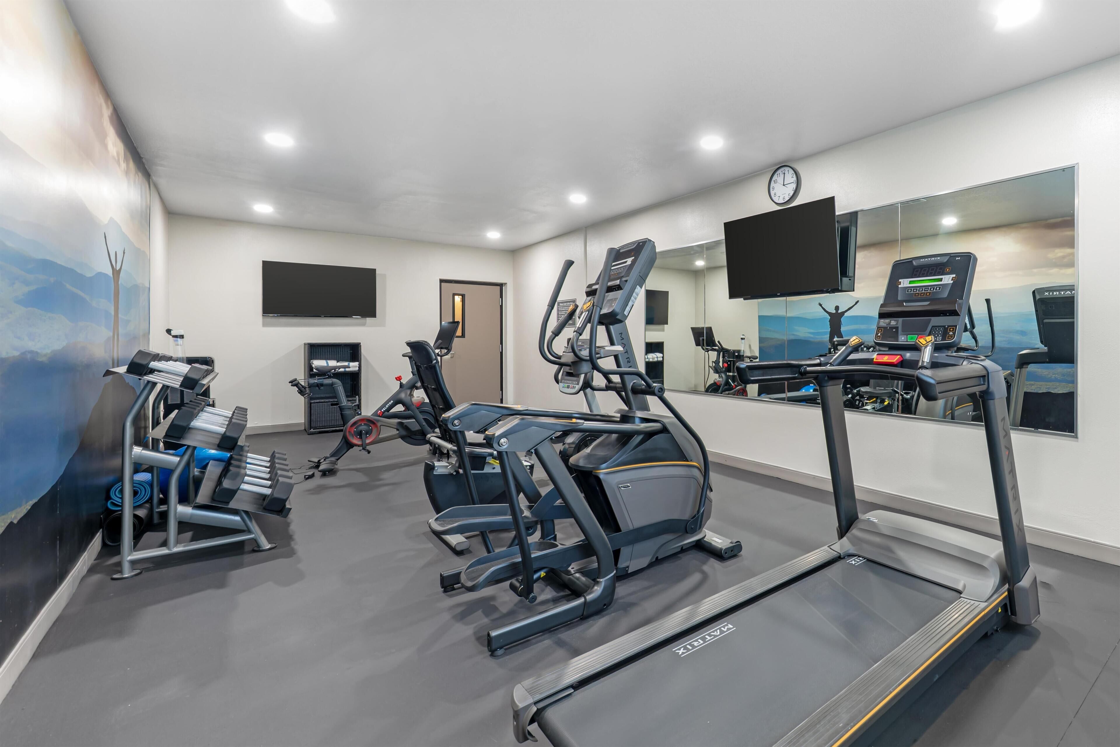 Un gimnasio con cintas de correr, elípticas y bancos de pesas.