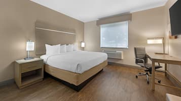 Una habitación de hotel con una cama grande, mesitas de noche con lámparas, un escritorio y una silla.