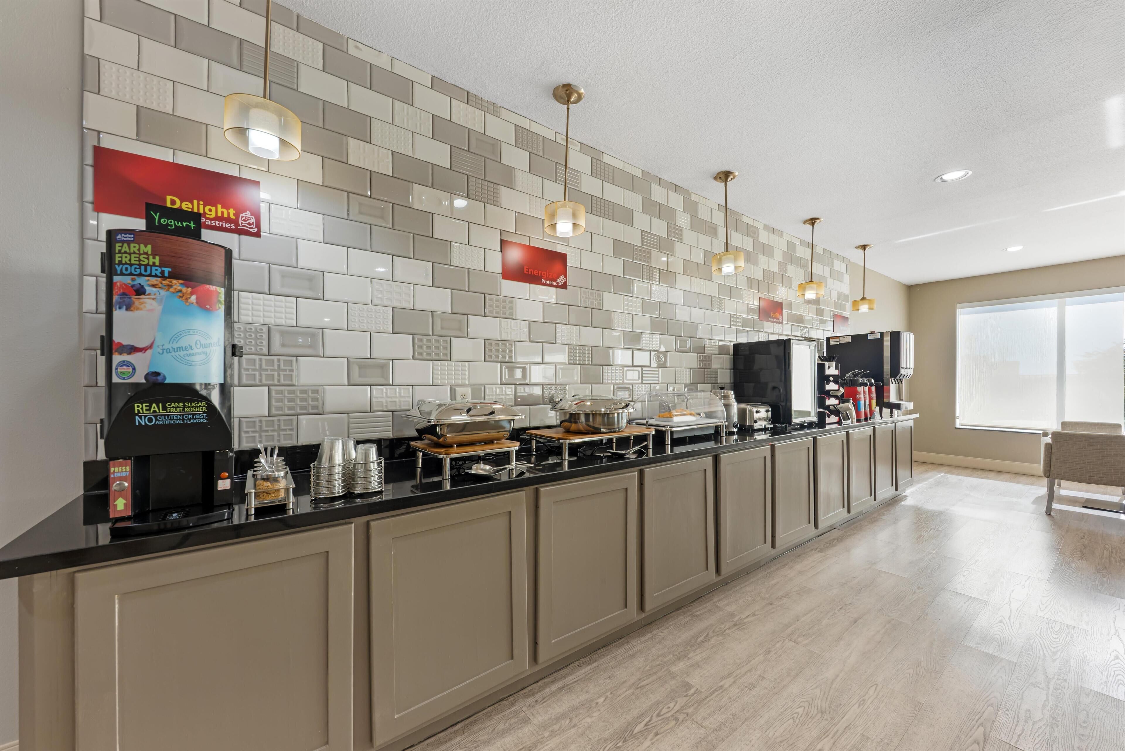 A modern kitchen with a long counter, various appliances, and a tiled backsplash.